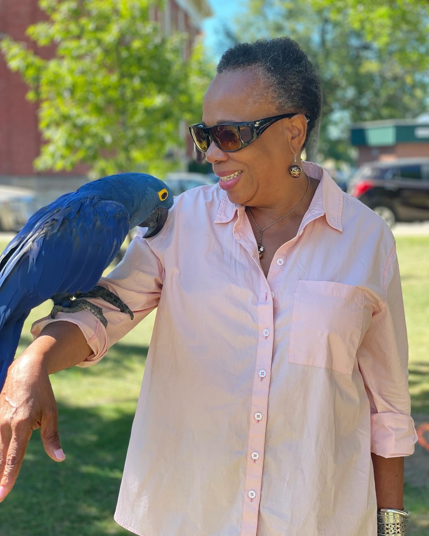 Angela Grogan, Port Hope mayoral candidate 2026, smiles with a blue macaw parrot on her arm.